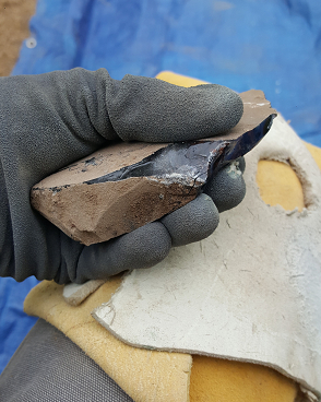 hand holding an obsidian flake with a platform